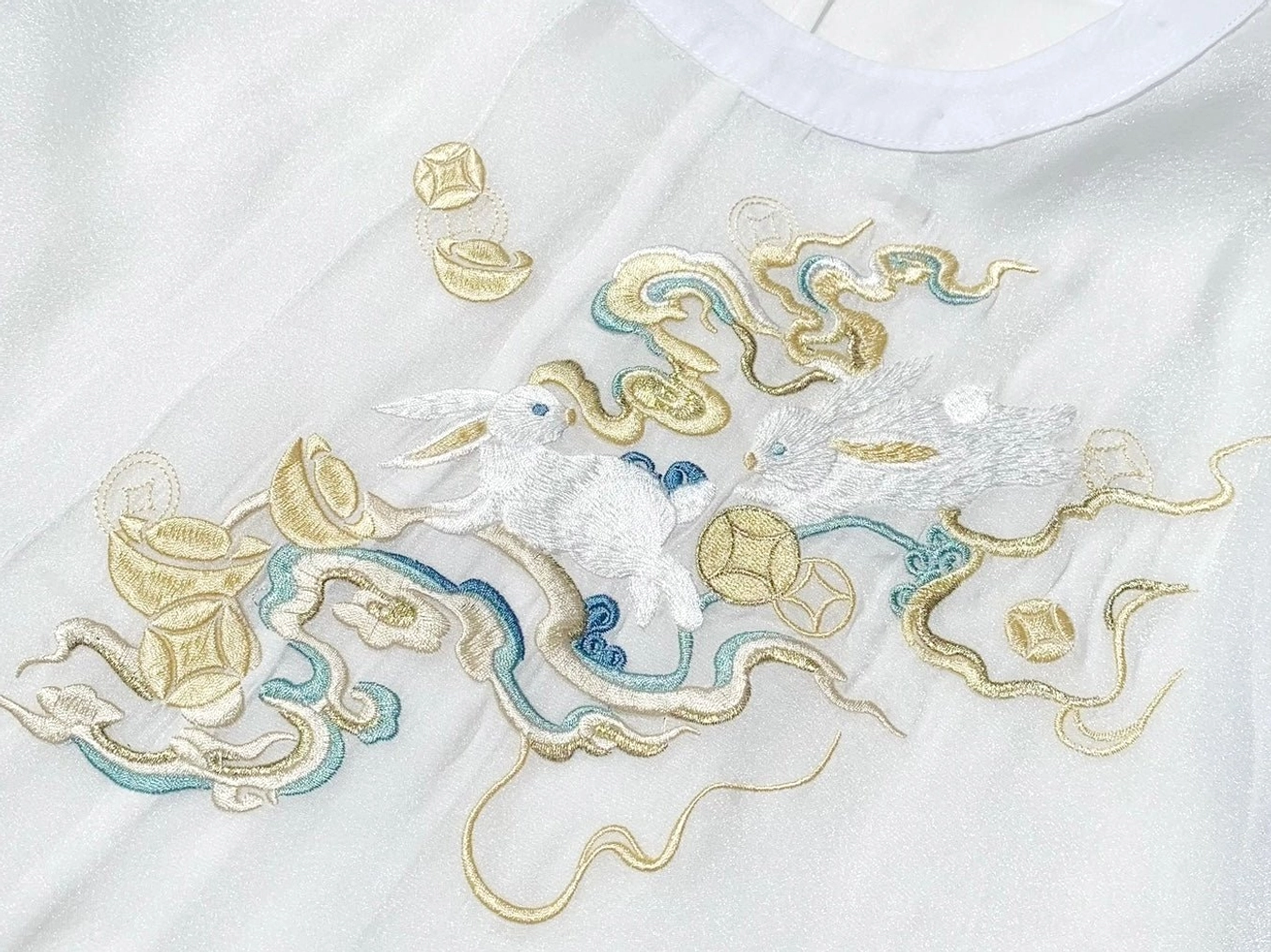 Close up of celestial xianxia hanfu embroidery featuring jade rabbit cloud patterns and traditional Chinese coin motifs