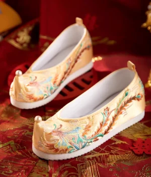 Front view of champagne Chinese wedding shoes with colorful phoenix embroidery pearl toe detail and white sole for Hanfu bridal outfit