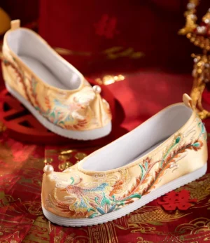 Champagne phoenix embroidered Chinese bridal Hanfu shoes with pearl upturned toe and white rubber sole on red wedding background