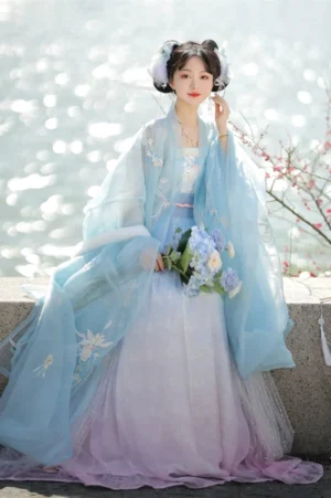 Blue Tang Dynasty style heziqun Hanfu dress set with flowing large sleeve coat and pink blue gradient skirt by a lakeside