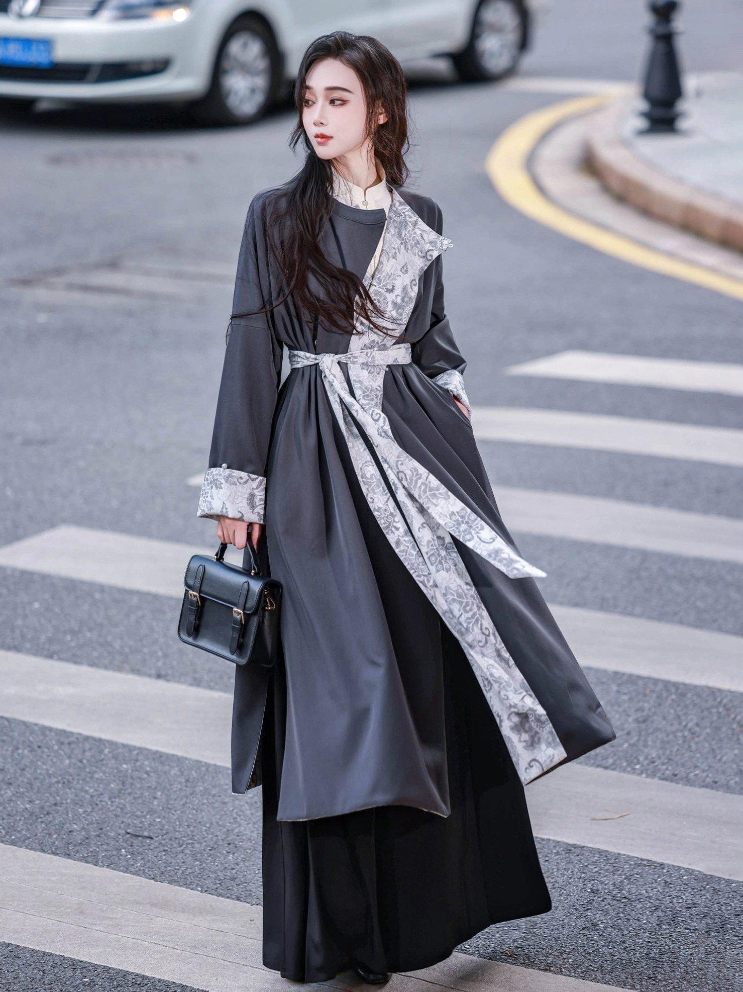Female model wearing the solid charcoal gray side of a reversible Hanfu round collar robe with stand collar inner layer printed sash and contrast cuffs