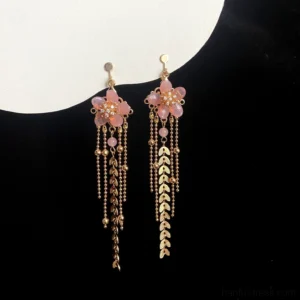 Cherry blossom dangle Hanfu earrings with pink floral tops, gold beaded centers, layered tassels, and wheat leaf chains displayed on black fabric