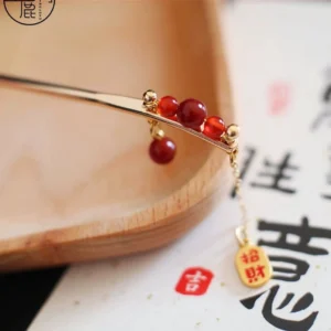 Chinese blessing hair stick with red agate beads gold tone frame and wealth blessing tassel charm on calligraphy background