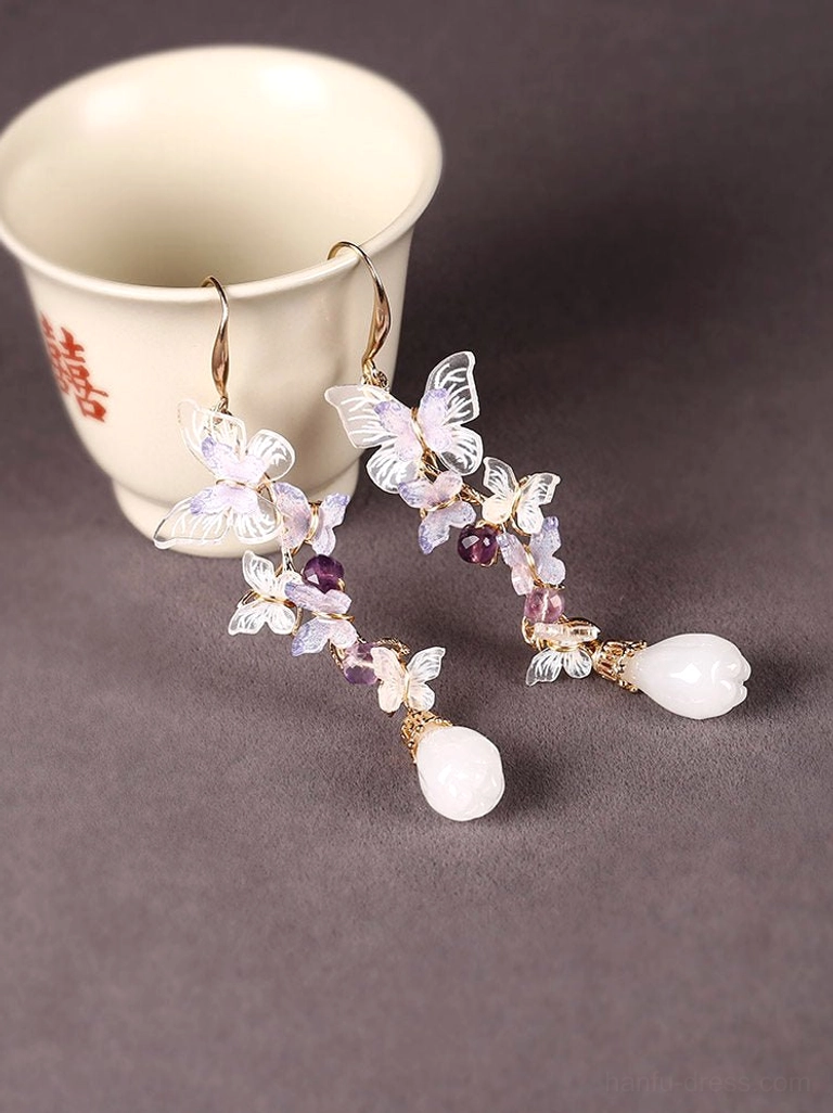 Chinese-inspired butterfly earrings styled beside a vintage Chinese teacup, showing purple butterfly charms, beadwork and elegant teardrop pendants