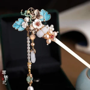 Chinese cloisonne blue flower jade gourd tassel hairpin with pearl beads and gold tone metal displayed beside a black jewelry box