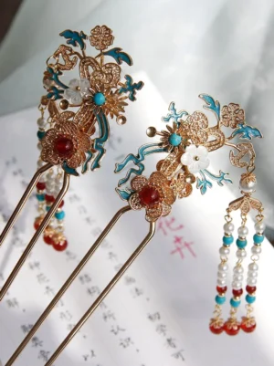 Close-up of Chinese cloisonne-style hair sticks with gold floral frames blue enamel decoration white shell flower and detachable beaded tassel