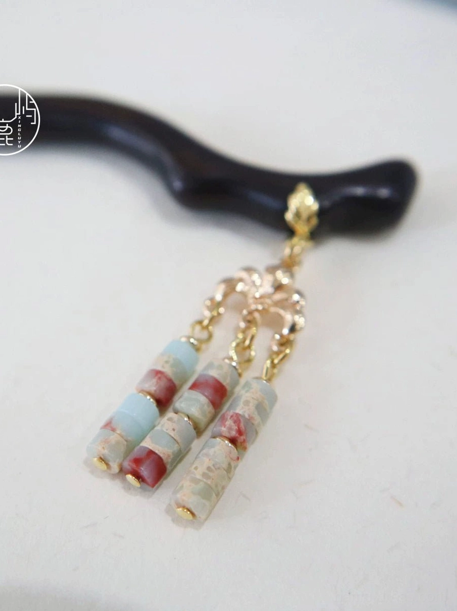 Chinese hair stick product display on a white background with a curved dark wooden shaft, gold floral connector, and three marbled stone tassel beads
