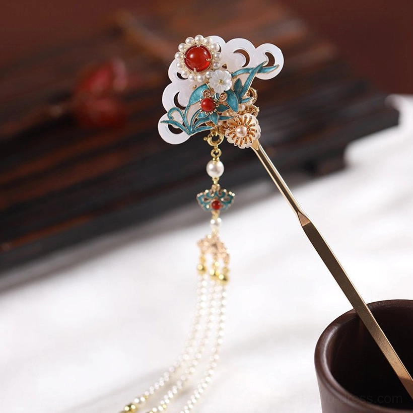 Three-quarter overhead view of a Chinese hair stick with simplified hanging tassel, gold-tone cloud ornament, pearl accents, and classical hair accessory details