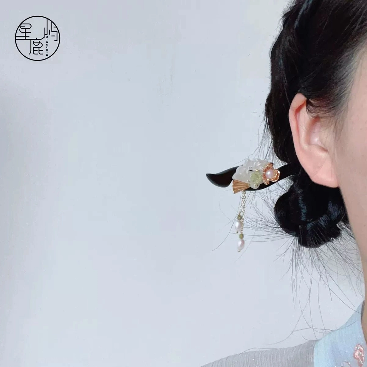 Traditional Chinese hair stick worn securely in a coiled bun with floral ornament and pearl tassel, styled with an elegant Hanfu outfit