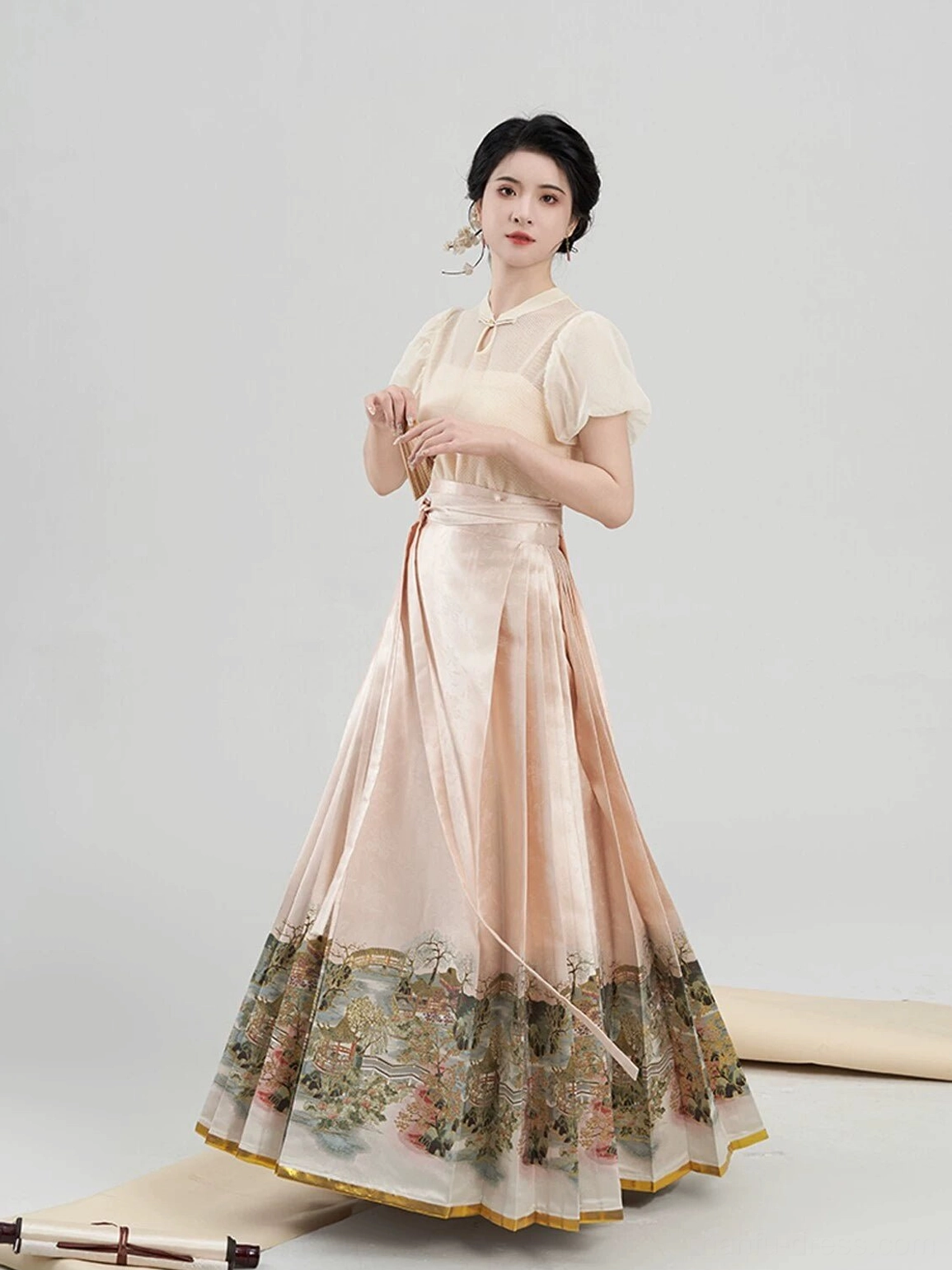 Close front view of a modern Chinese hanfu blouse with sheer puff sleeves, jade inspired pendant collar fastener, pleats, and landscape print skirt hem