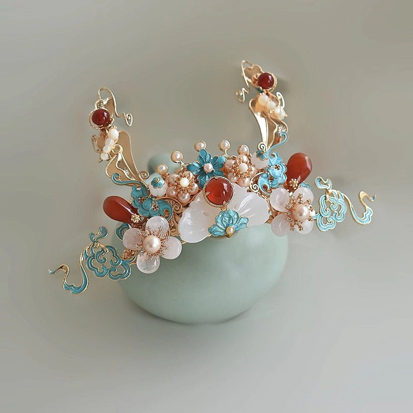 Close up view of a Chinese Hanfu hair crown featuring flying apsara motifs, blue cloisonne style clouds, red beads, white jade inspired accents, and freshwater pearls