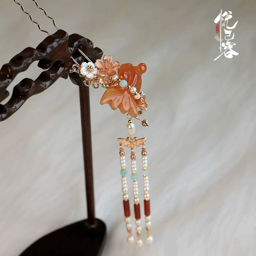 Single Chinese-style Hanfu hair pin with carved orange agate flower ornament, tiny floral beads, pearls, red agate beads, and hanging tassels on a jewelry stand