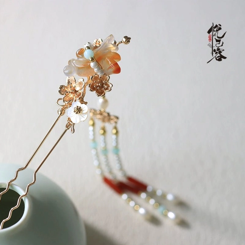 Detailed side view of a Chinese Hanfu hair pin with gold frame, carved agate flower, white shell beads, light blue accents, red agate, pearls, and tassels