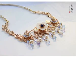 Chinese style Hanfu neck chain with hollow carved rose-gold metal links, delicate floral pendant, and flowing decorative bead tassels on a light background