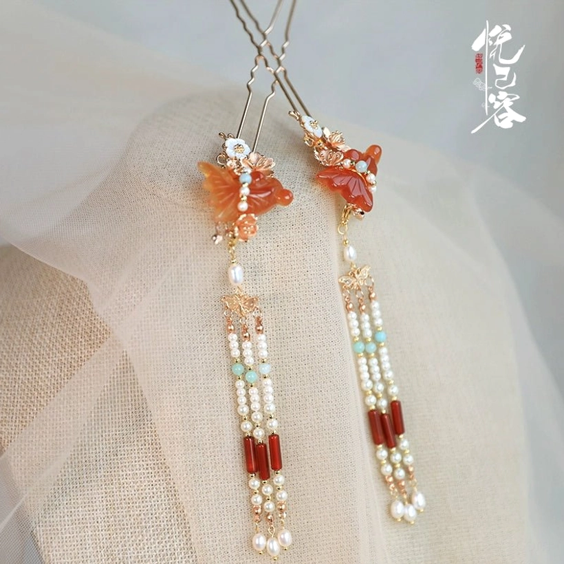 Classical Chinese Hanfu tassel hair pins with gold-toned frames, orange agate butterfly ornaments, pearl strands, and red agate beads displayed on linen fabric