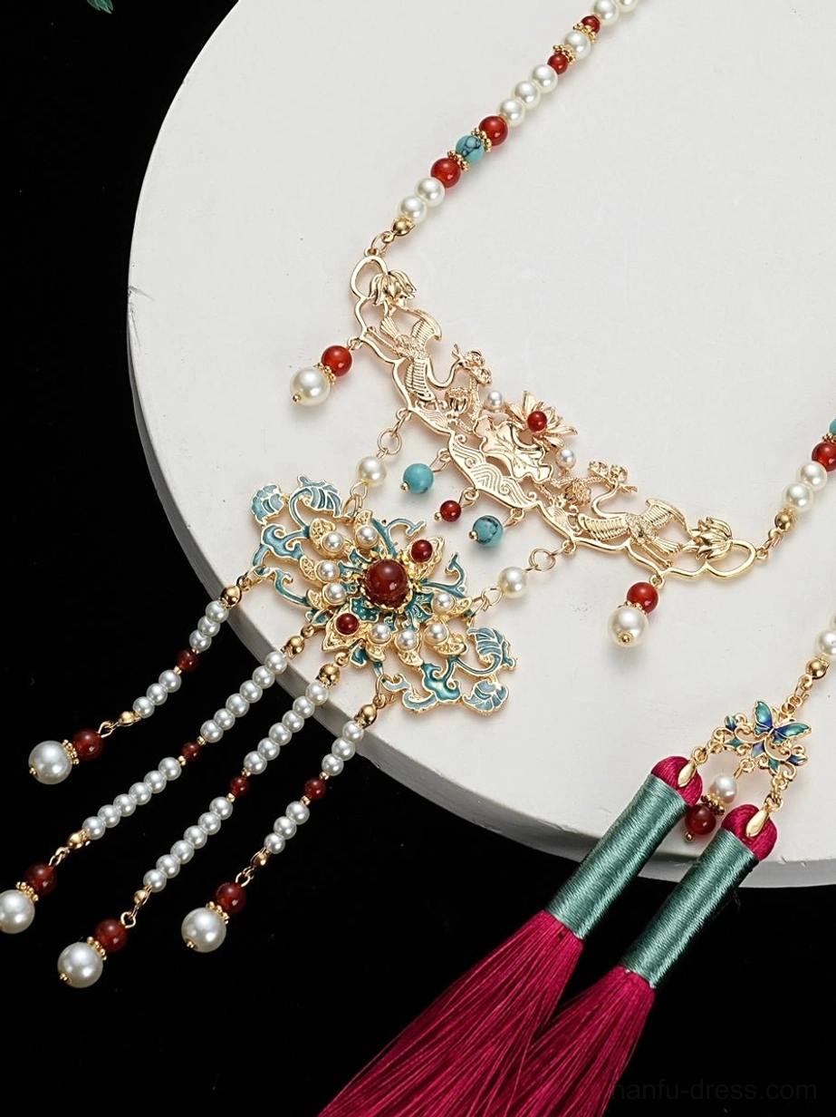 Close-up side view of a Chinese hanfu tassel necklace showing pearl-style beads, gold cloisonne floral pendant, rose-red tassel, and green wrapping details