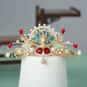 Traditional Chinese Hanfu wedding hair crown displayed on a white stand with gold-tone metal, faux pearls, red beads, blue cloisonne-inspired details, jade-like accents, and a hanging bell pendant