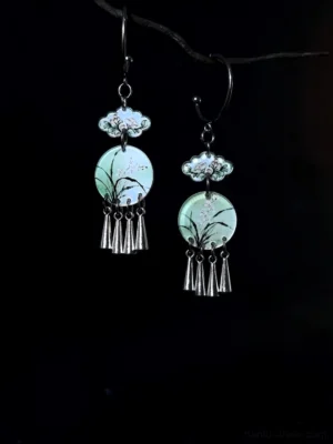 Chinese ink orchid drop earrings with light green round pendants, silver cloud-shaped links, and delicate tassel charms shown against a black background