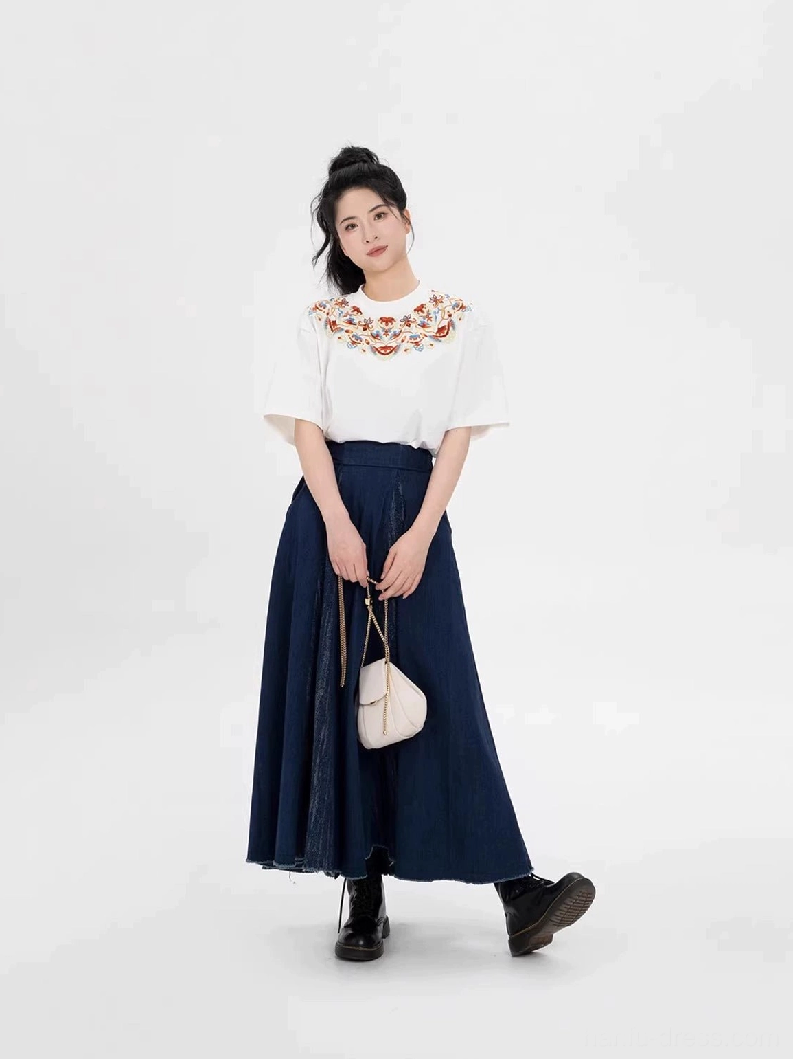 Three-quarter side view of a Chinese-inspired embroidered T-shirt and flowing navy maxi skirt with raw frayed hem
