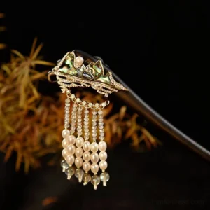 Traditional Chinese hair stick with black wooden shaft, enamel mountain landscape ornament, central pearl, rhinestone trim, and flowing gray-blue bead tassel on a dark decorative background