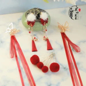 Complete Chinese New Year Hanfu hair accessory set in red and gold with tassels, white pom-poms, hair clips and hair pins displayed on marble