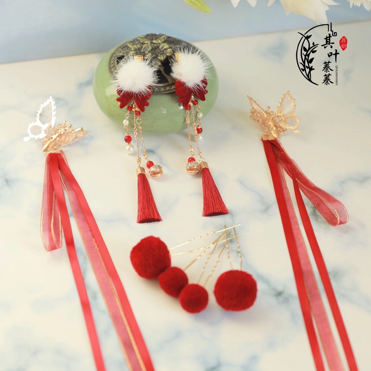 Complete Chinese New Year Hanfu hair accessory set in red and gold with tassels, white pom-poms, hair clips and hair pins displayed on marble