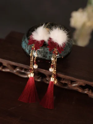 Close-up of red tassel Hanfu hair clips with white plush pom-poms, red flower details, pearl-like beads and gold-tone chains
