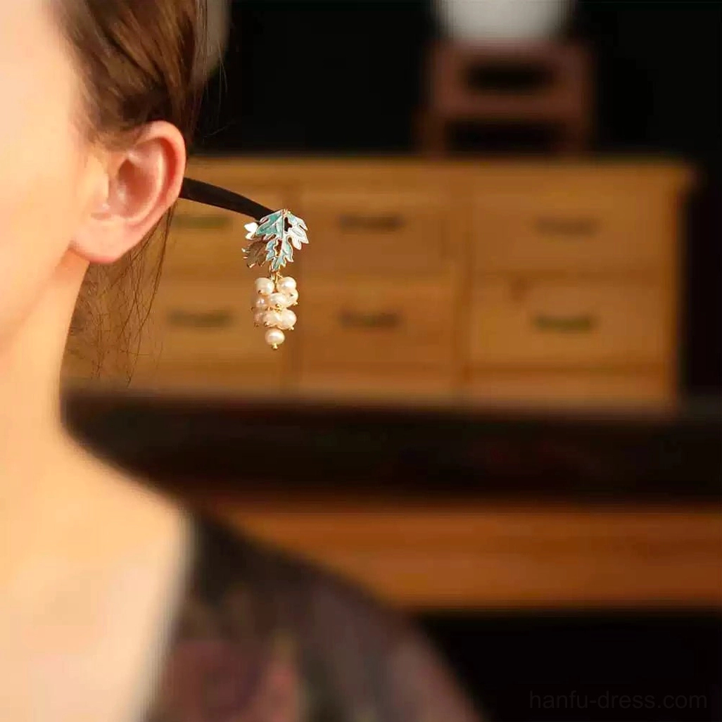 Side view of a model wearing a Chinese pearl grape hair stick with the imitation pearl pendant hanging elegantly beside the ear