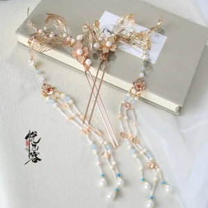 Chinese phoenix flower tassel hairpin displayed on a beige book, showing matching openwork feather and floral metal details with pearl embellishments