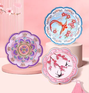 Set of Chinese pocket mirrors with scalloped flower-shaped frames, bird and blossom artwork, cloisonne-style colours, gold-tone details, and decorative tassel charms displayed on a pink Chinese-style background