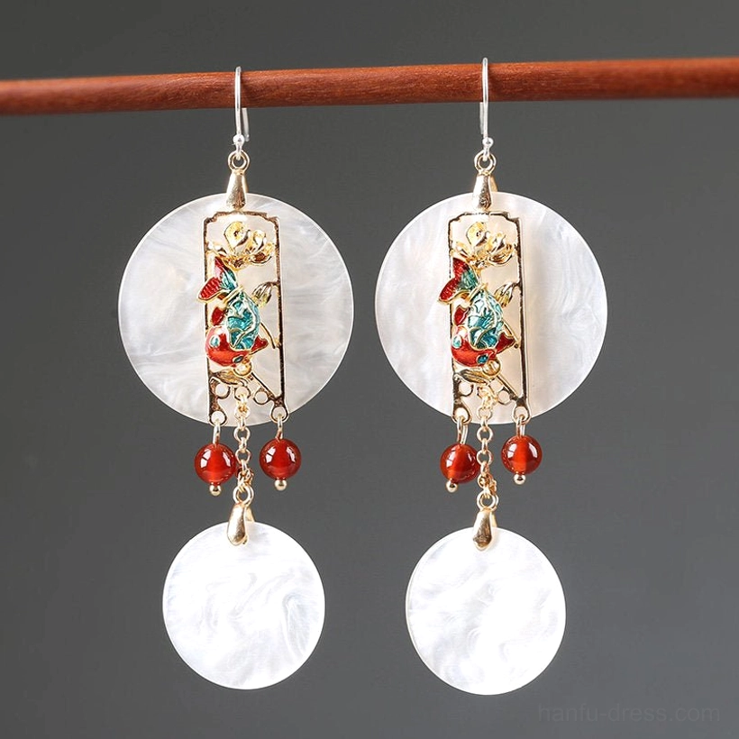 Pair of Chinese shell earrings hanging from a wooden rod with glossy white pendants gold-tone details and red beads