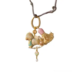 Traditional Chinese Song brocade rocking horse bag charm and keychain with patterned light brown brocade fabric, gold-toned hardware, pink tassel, pearl-style pendant, and decorative beads displayed against a white background