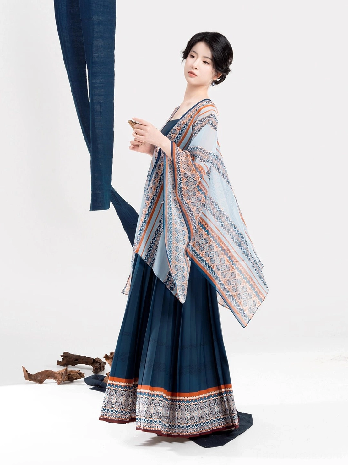 Three-quarter side view of a Chinese-style ethnic Hanfu outfit featuring a dark blue pleated slip dress and fully patterned light blue shawl