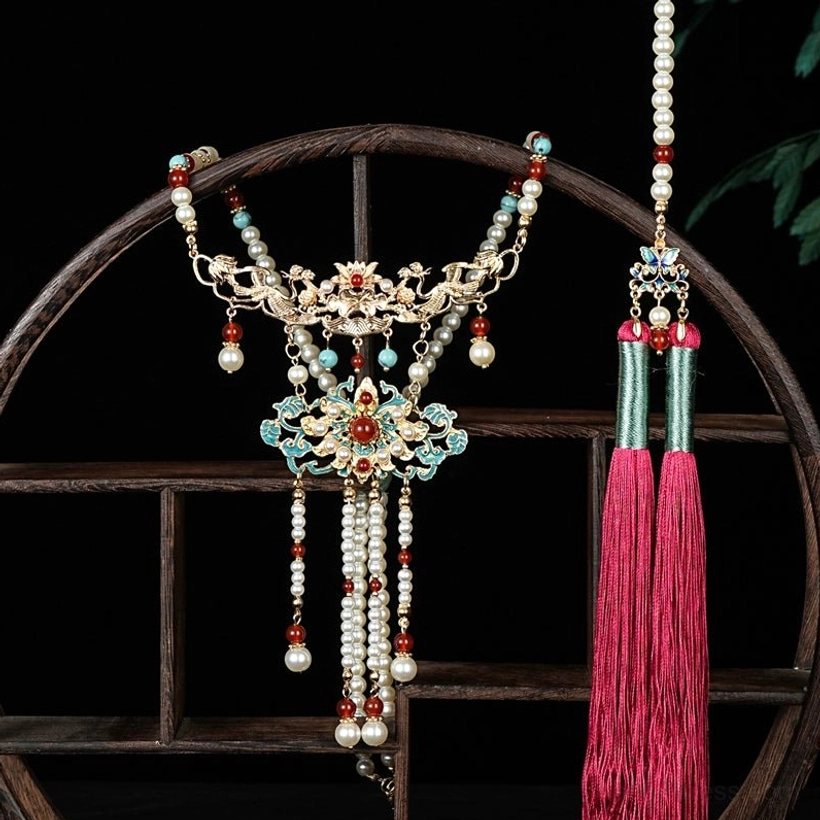 Side full view of a Chinese-style hanfu necklace with gold-toned base, cloisonne floral motifs, pearl-style and red bead accents, and flowing rose-red tassel pendants