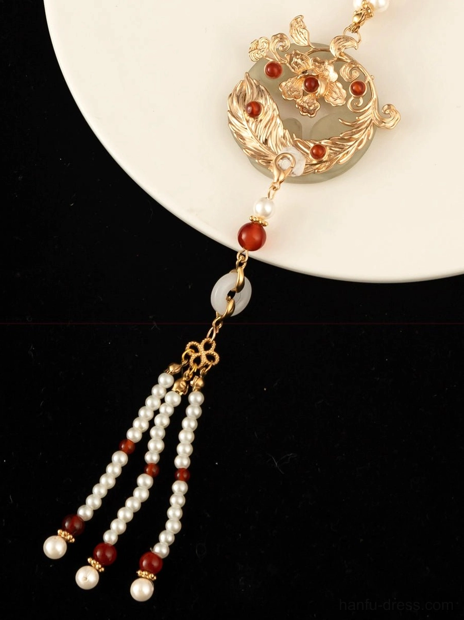 Close-up of Chinese style necklace multi-strand tassel with red agate white pearl beads gold connectors and jade circular charm