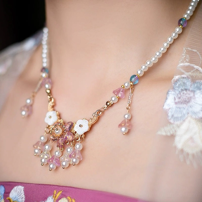Woman wearing a vintage Chinese style pearl and tassel necklace with embroidered floral Hanfu, showing the elegant matching effect of traditional Chinese jewelry and clothing