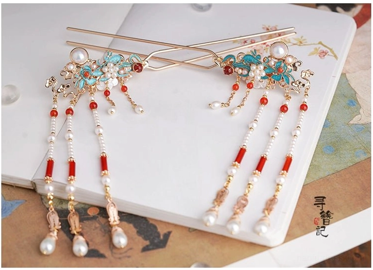 Overhead view of Chinese-style tassel hairpins showing blue floral decoration, pearl embellishments, red agate accents, gold-toned details, and layered hanging tassels