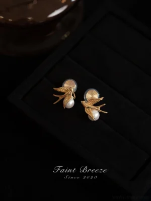 Chinese swallow earrings with white pearls and earring backs shown in a detailed flat lay jewelry display