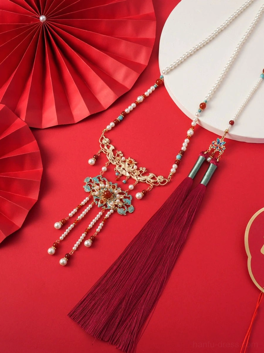 Top view of Chinese wedding Hanfu necklace with layered gold tone chains floral cloisonne pendants red beads pearl accents and dark red tassel