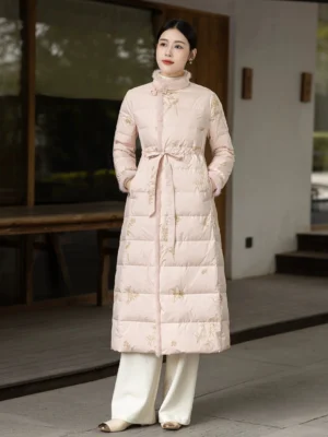 Chinese Zen-inspired women's winter down coat in pale pink with floral embroidery, soft fuzzy collar trim, tailored waist, and practical pockets in a traditional courtyard