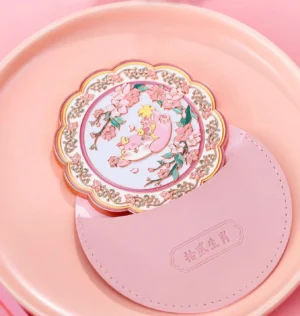 Chinese zodiac blessings pocket mirror with protective pouch displayed on a pink ceramic tray, featuring pastel floral animal artwork
