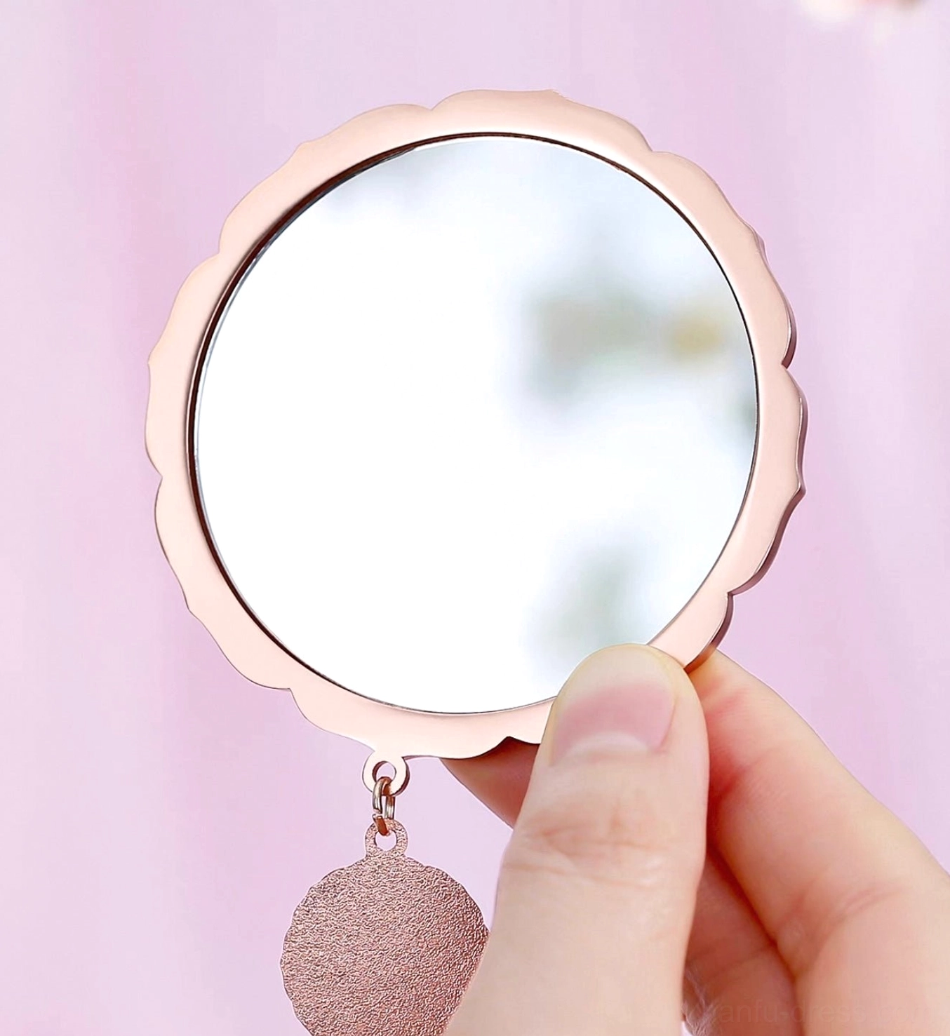 Close view of Chinese zodiac blessings pocket mirror showing the clear round mirror, rose gold scalloped frame and glitter hanging charm