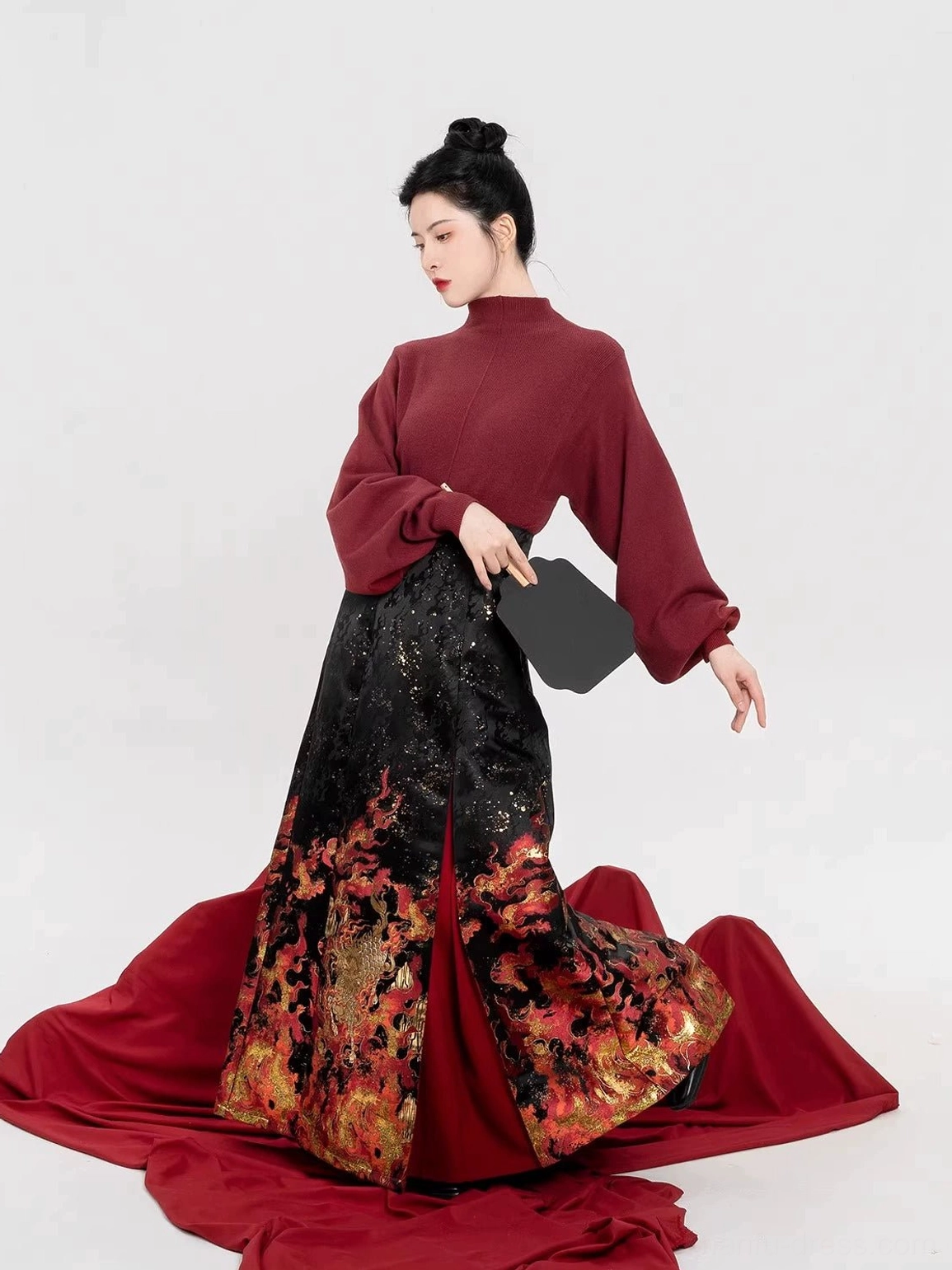 Side view of burgundy turtleneck top and black pleated dragon flame mamian skirt Chinese Hanfu outfit with fan