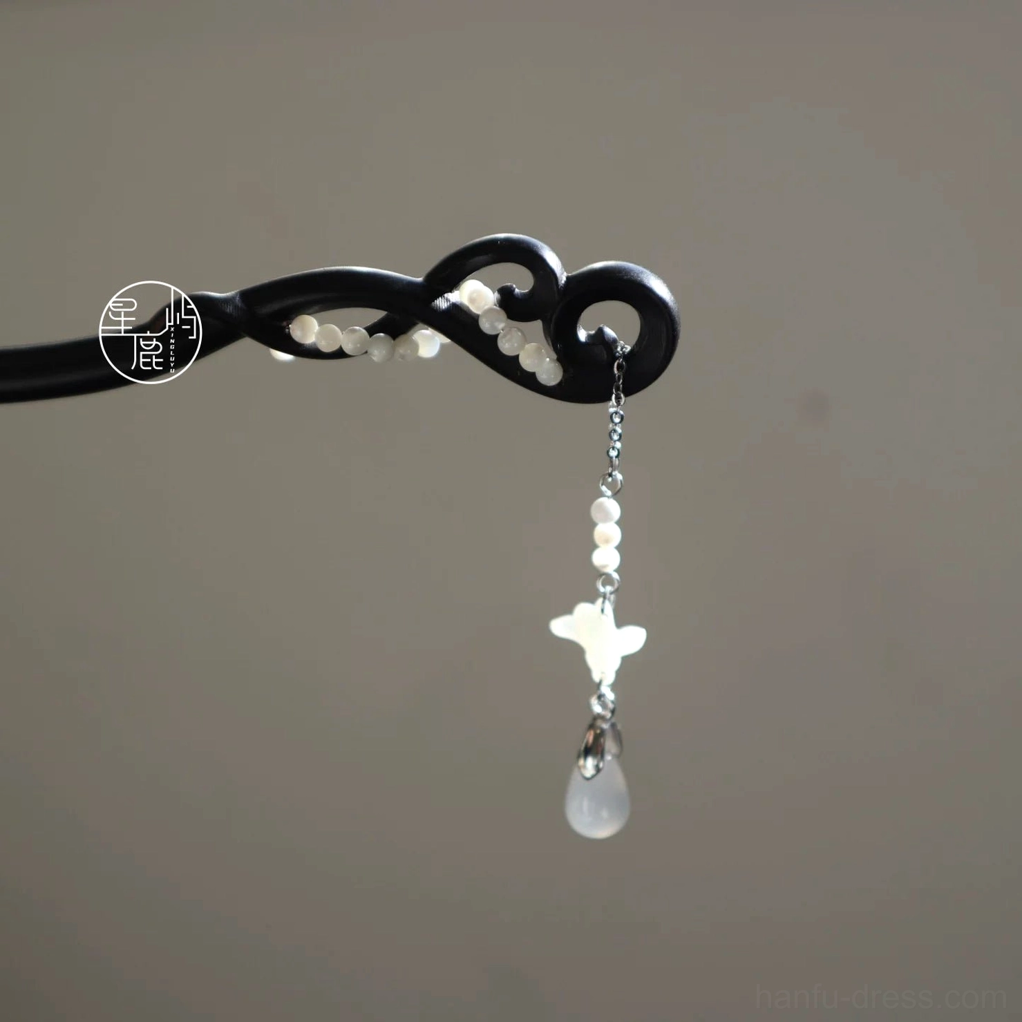 Classic Chinese wooden hair stick with twisted black carved shaft, white decorative beads, and matching silver chain tassel displayed on a neutral background