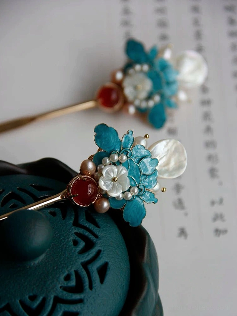 Close-up side view of a classical Chinese peony hair stick with blue floral enamel details, white shell accents, freshwater pearls, and red agate decoration