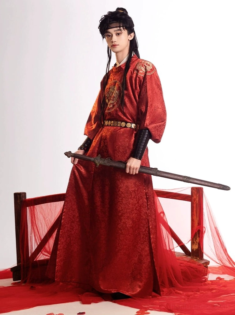 Side three-quarter portrait of male model in red Tang Dynasty dragon round-collar robe styled with dark arm guards and a traditional sword