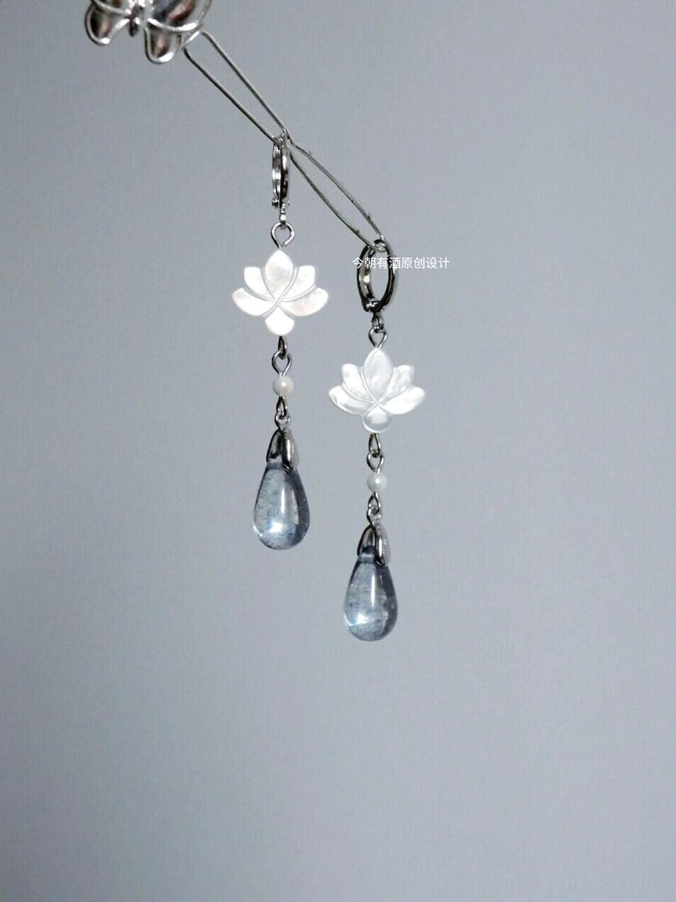 Clear lotus drop Hanfu earrings with carved white shell flower charms faux pearl accents smoky blue glass teardrops and silver hook ear wires