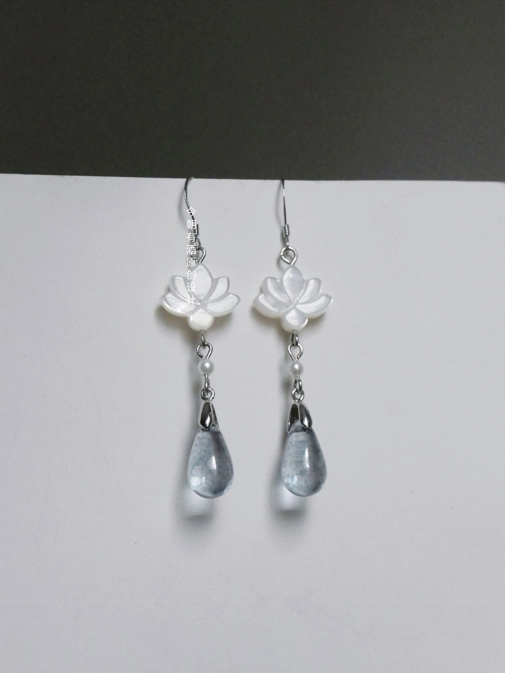 Pair of clear lotus drop earrings for Hanfu featuring white shell lotus charms pearl details smoky blue teardrop pendants and silver hooks