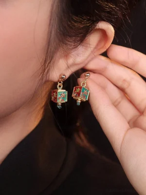 Woman wearing gold-tone floral cube drop Hanfu earrings with blue dangling accents shown in a close-up side view