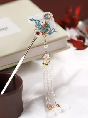 Cloisonne orchid tassel Chinese hair stick for Hanfu displayed on a book with blue floral enamel-style ornament, white accents, pearl-style tassel and gold-tone pin